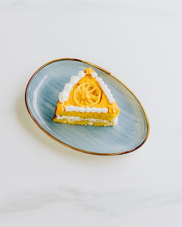 A slice of layered sponge with mango cream and a candied citrus wheel on top