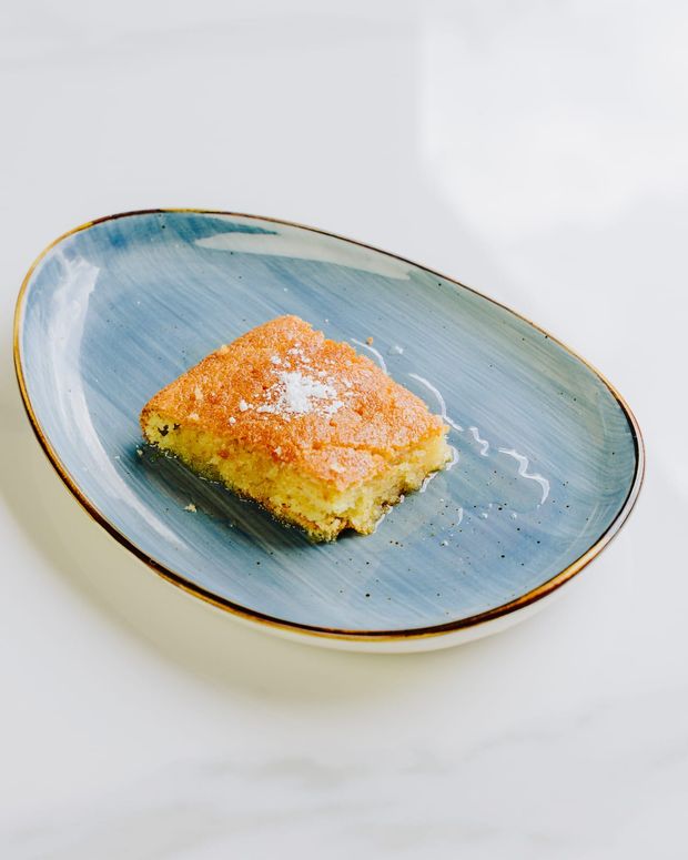 A square of syrup-soaked semolina cake dusted with icing sugar