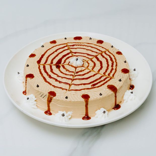 A whole cake finished in caramel buttercream with a feathered caramel spiderweb pattern