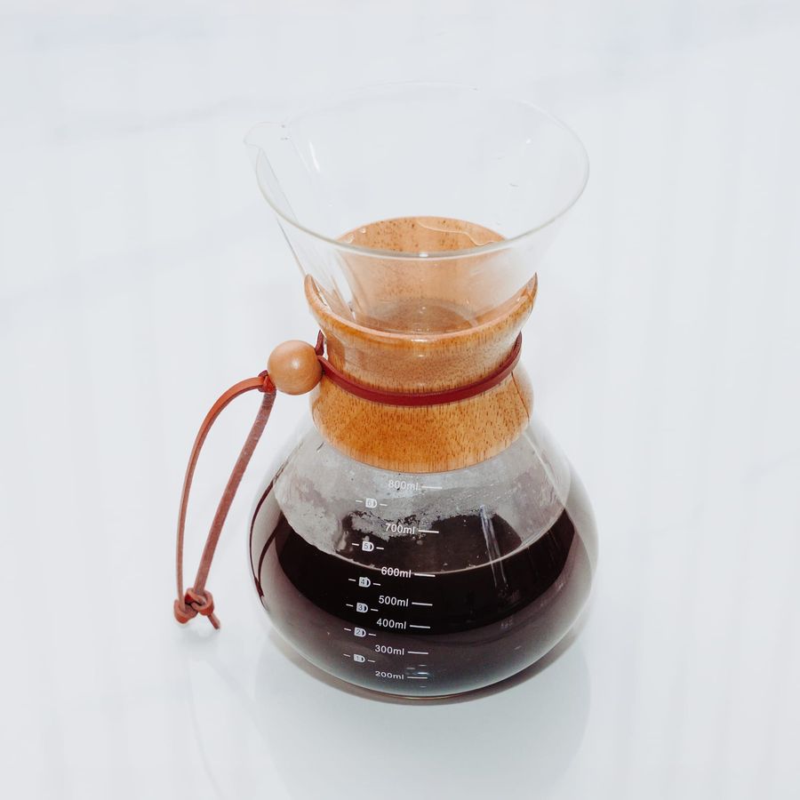 A Chemex brewer with a wooden collar and leather tie, filled with freshly brewed black coffee