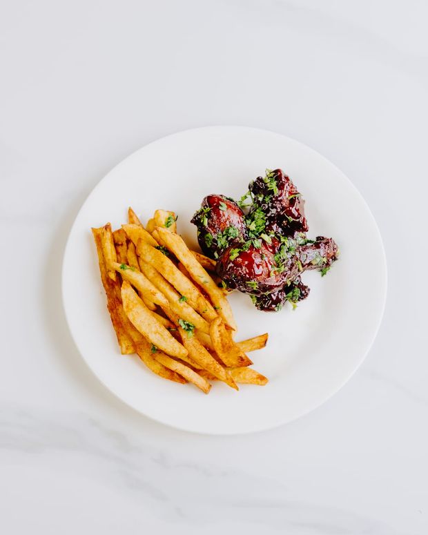 BBQ-glazed chicken pieces sprinkled with coriander, served with a row of seasoned fries