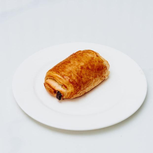 A golden, glossy pain au chocolat with dark chocolate visible at the end