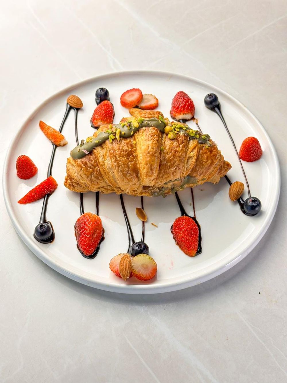 A croissant finished with pistachio cream and chopped pistachios