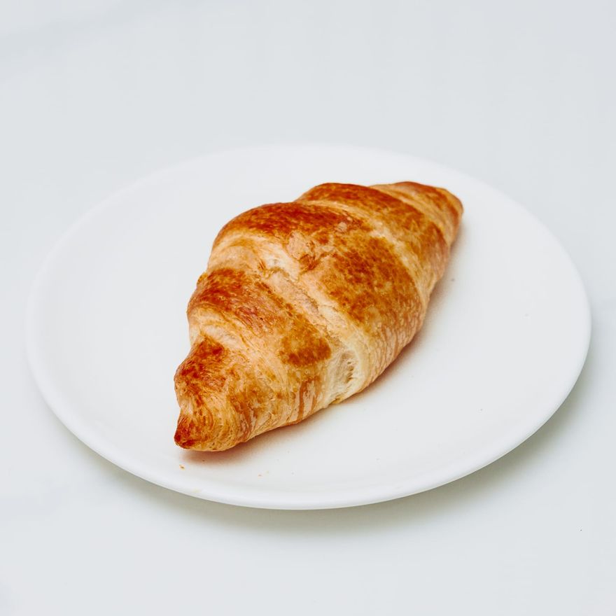 A plain butter croissant on a white plate