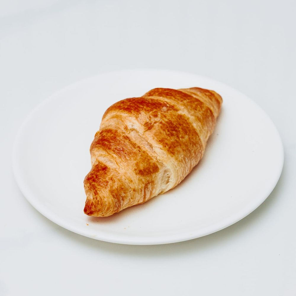 A plain butter croissant on a white plate