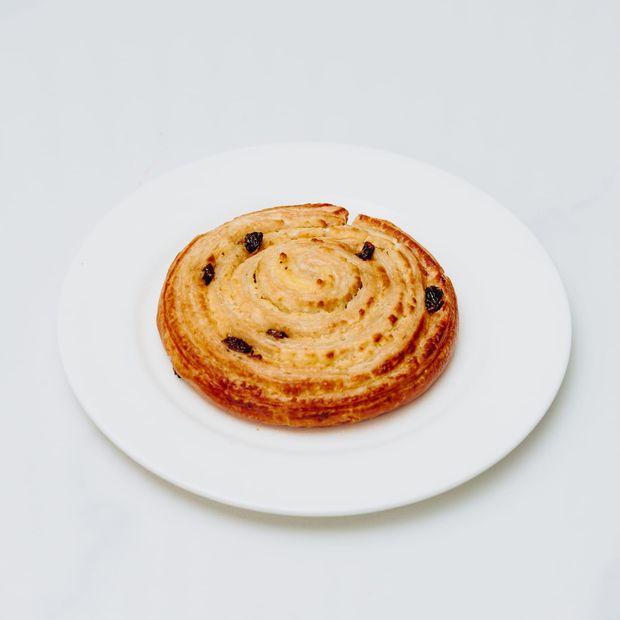 A spiral raisin danish with a glossy glaze and a custard swirl through the centre