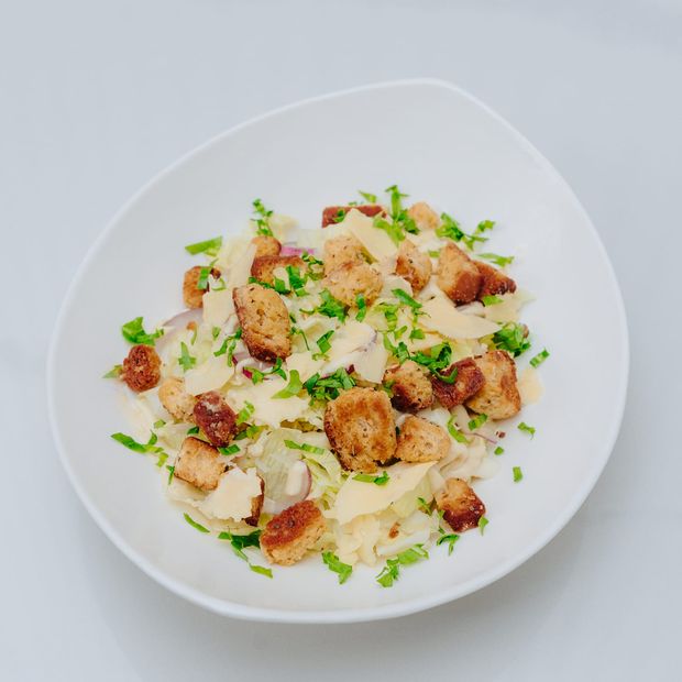 A Caesar-style salad with crisp lettuce, croutons, shaved parmesan and creamy dressing