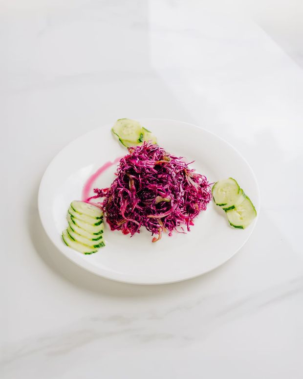Shredded red cabbage slaw with sliced onion, pink dressing and fanned cucumber