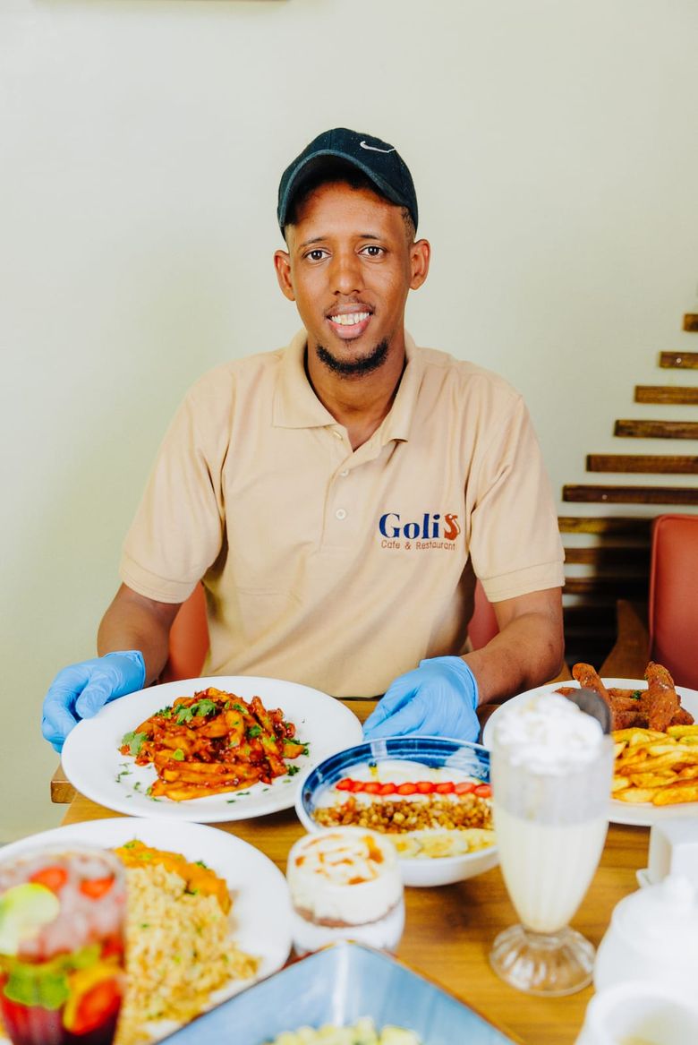 A member of the Café Golis team in branded uniform presenting a plate of masala chips